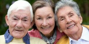 Old couple and their daughter smiling outdoors